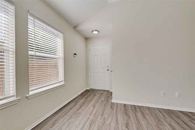 unfurnished room featuring vaulted ceiling and light wood-type flooring