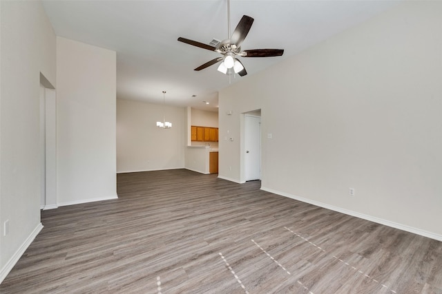 unfurnished living room featuring hardwood / wood-style floors and ceiling fan with notable chandelier