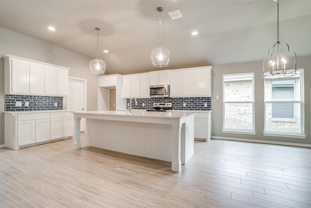 kitchen featuring white cabinetry, light hardwood / wood-style flooring, a center island with sink, and appliances with stainless steel finishes