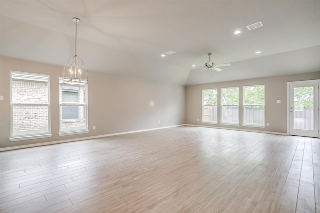 unfurnished room featuring plenty of natural light, vaulted ceiling, ceiling fan with notable chandelier, and light hardwood / wood-style flooring