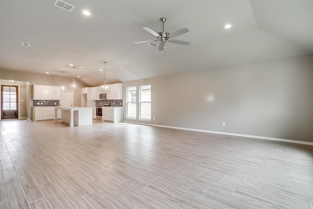 unfurnished living room with ceiling fan, lofted ceiling, a wealth of natural light, and light hardwood / wood-style flooring