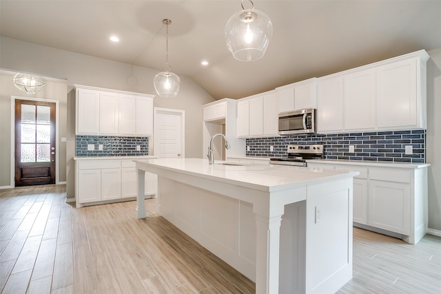 kitchen featuring appliances with stainless steel finishes, light wood-type flooring, sink, pendant lighting, and white cabinets