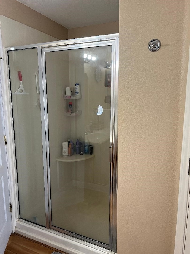 bathroom featuring a shower with door and wood-type flooring