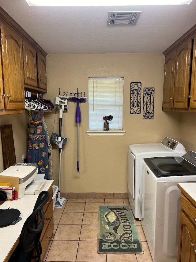 clothes washing area featuring cabinets, washing machine and dryer, and light tile patterned floors