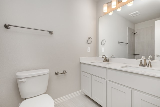 bathroom with tile patterned flooring, vanity, toilet, and a tile shower