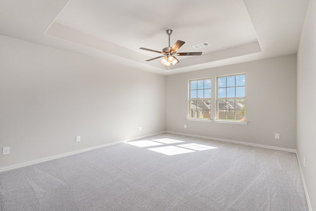 carpeted empty room with a tray ceiling and ceiling fan