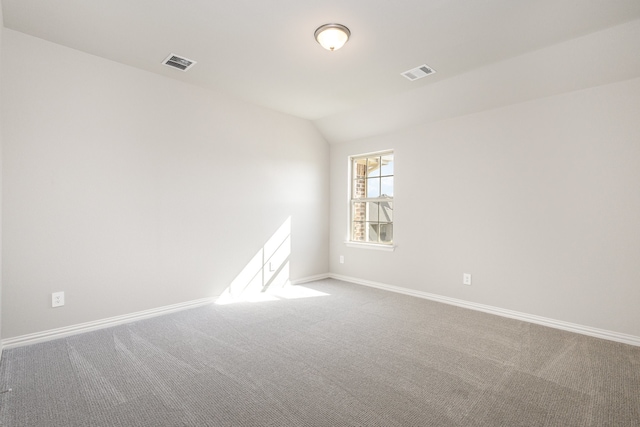 carpeted spare room featuring lofted ceiling