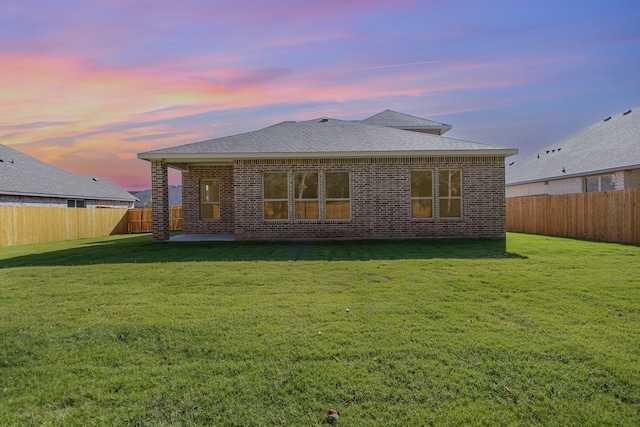 back house at dusk featuring a yard