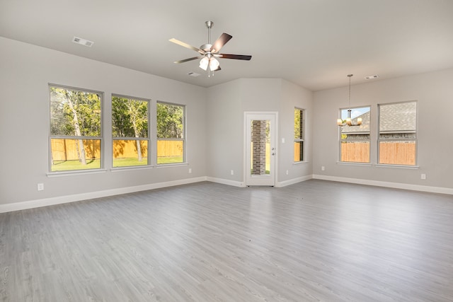 unfurnished living room featuring ceiling fan with notable chandelier and hardwood / wood-style flooring