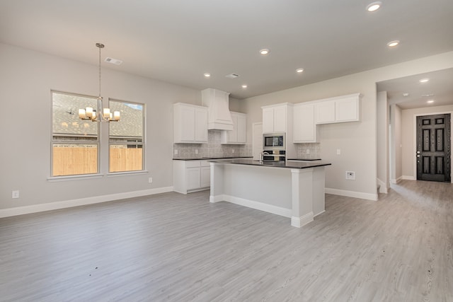 kitchen featuring tasteful backsplash, stainless steel appliances, decorative light fixtures, light hardwood / wood-style flooring, and white cabinets