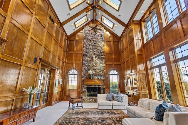 living room with ceiling fan, high vaulted ceiling, wood walls, light carpet, and a fireplace