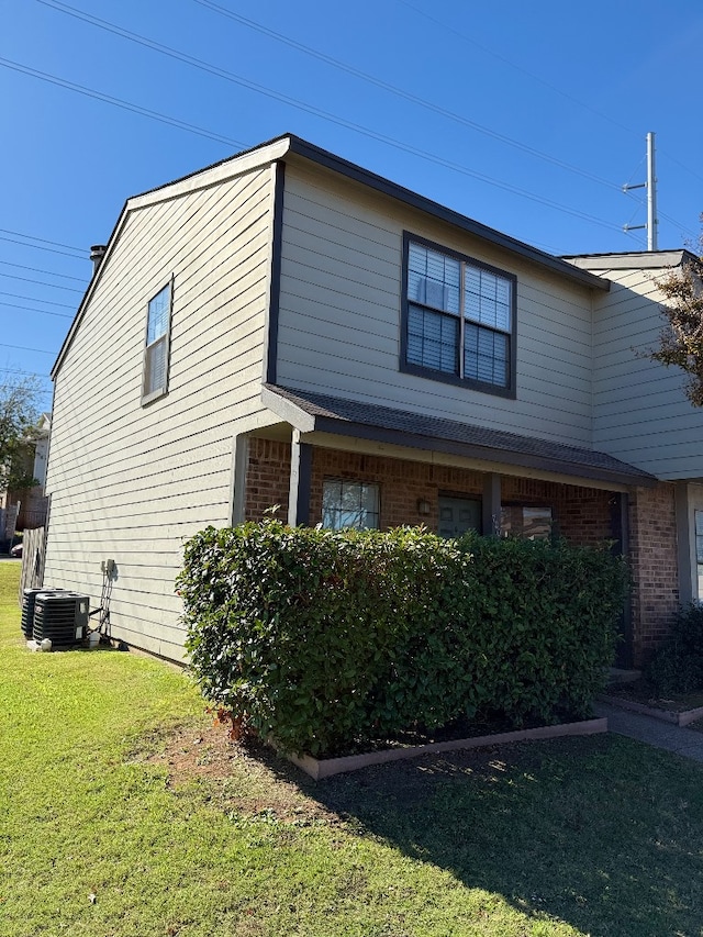 view of side of home with a lawn and central AC