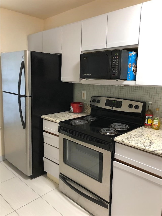 kitchen featuring light stone counters, white cabinets, light tile patterned floors, and appliances with stainless steel finishes