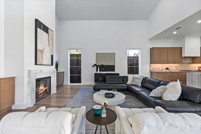 living room with a high end fireplace, dark hardwood / wood-style floors, and a high ceiling