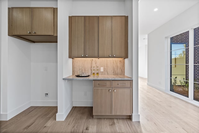 kitchen with tasteful backsplash, light stone countertops, and light wood-type flooring