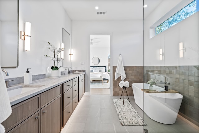 bathroom featuring a washtub, vanity, tile patterned floors, and tile walls