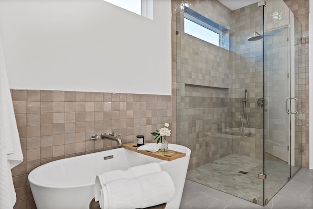 bathroom with tile patterned floors, tile walls, and shower with separate bathtub