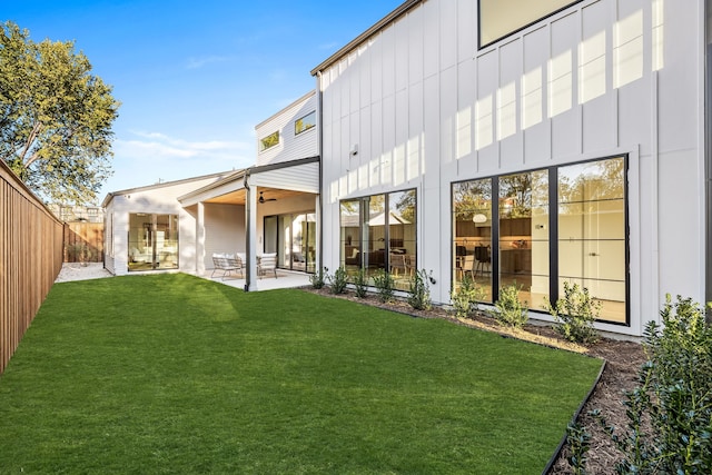 rear view of property featuring ceiling fan, a yard, and a patio