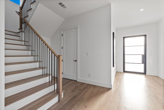 foyer entrance with hardwood / wood-style floors and vaulted ceiling