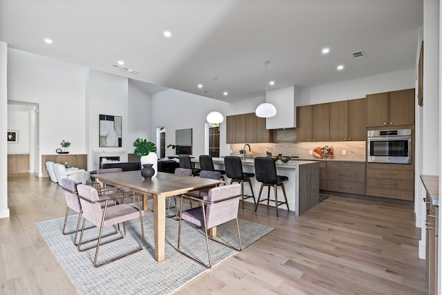 dining space with a towering ceiling, sink, and light hardwood / wood-style flooring