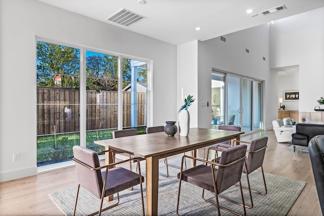 dining space featuring a towering ceiling and light hardwood / wood-style floors