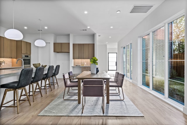 dining room featuring light wood-type flooring, plenty of natural light, and sink