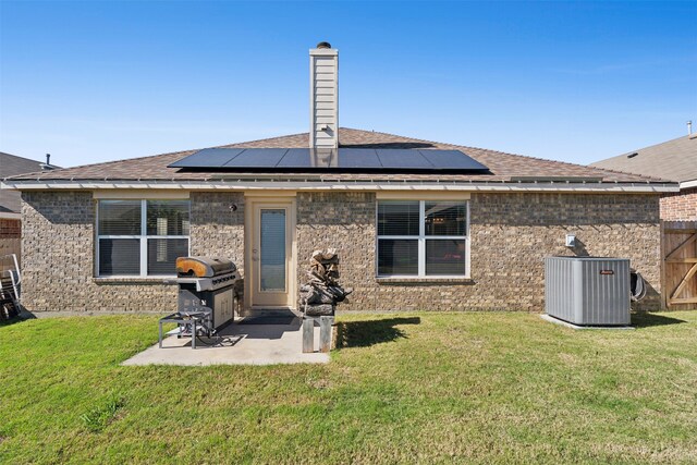 back of house with solar panels, cooling unit, a yard, and a patio