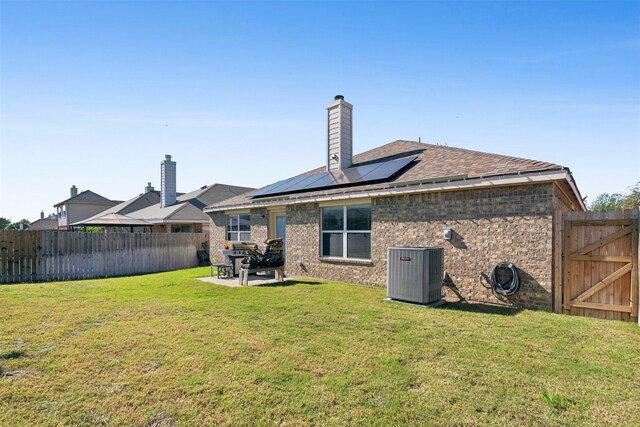 back of house with solar panels, a patio, a lawn, and central air condition unit