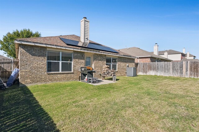 back of house featuring solar panels, a patio area, a yard, and central air condition unit