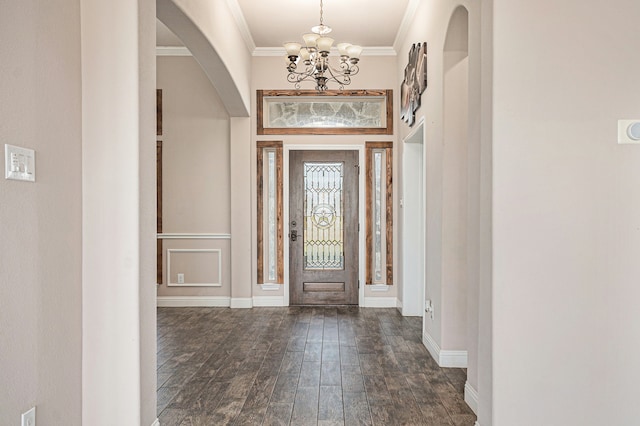 entrance foyer featuring dark hardwood / wood-style flooring, ornamental molding, and a chandelier