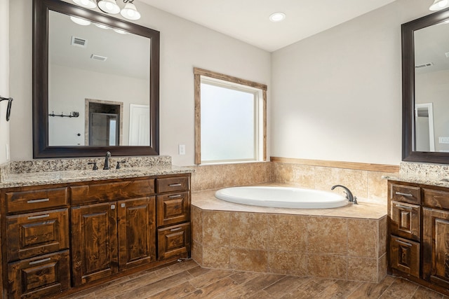 bathroom featuring vanity, hardwood / wood-style flooring, and tiled tub