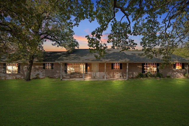 back house at dusk with a lawn and a patio