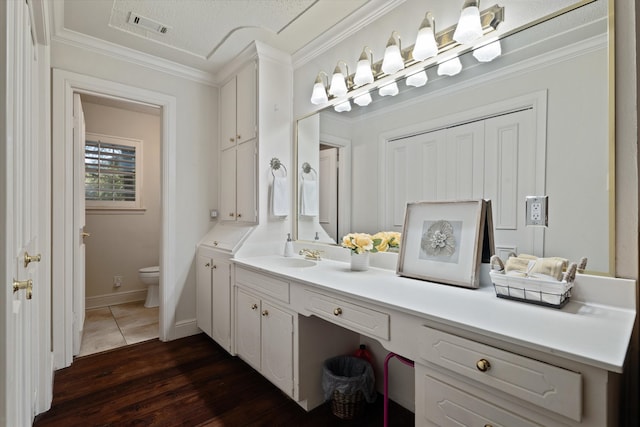 bathroom with vanity, a textured ceiling, crown molding, hardwood / wood-style floors, and toilet