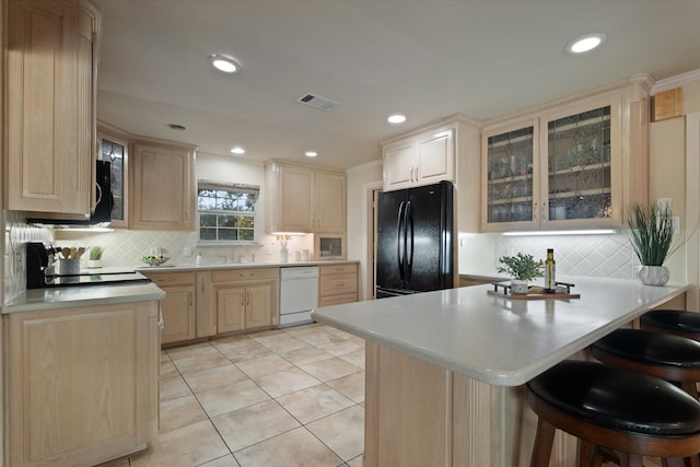 kitchen featuring kitchen peninsula, a kitchen breakfast bar, black appliances, light brown cabinets, and light tile patterned floors