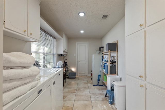 laundry room featuring cabinets, a textured ceiling, washing machine and dryer, and light tile patterned flooring