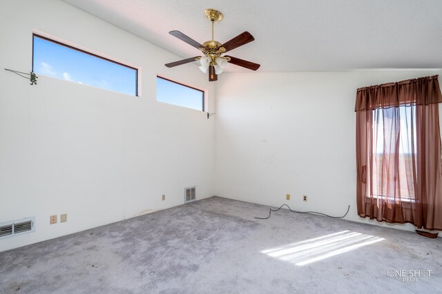 empty room featuring ceiling fan, lofted ceiling, and light carpet