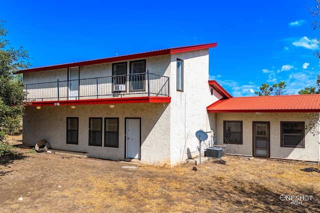 rear view of house featuring cooling unit and a balcony