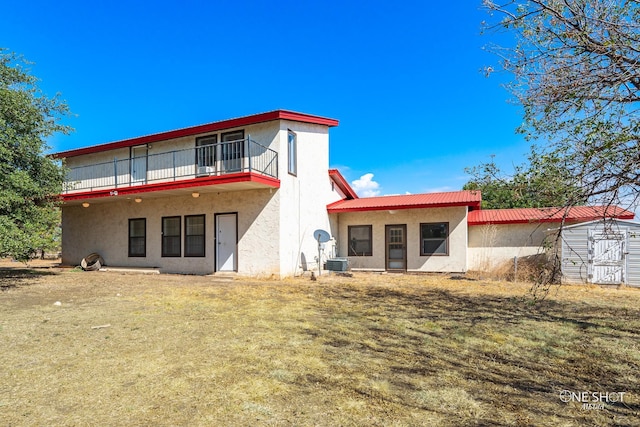 back of property with cooling unit, a balcony, and a yard