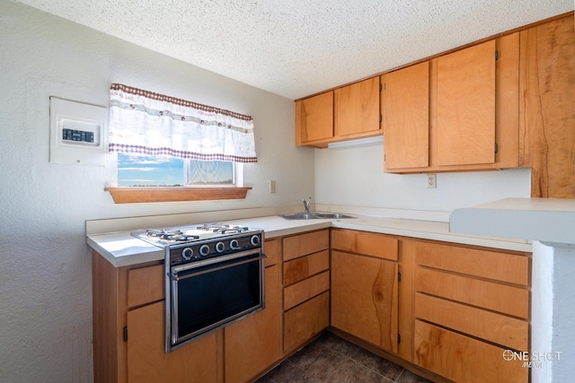 kitchen with sink, dark tile patterned floors, a textured ceiling, and range