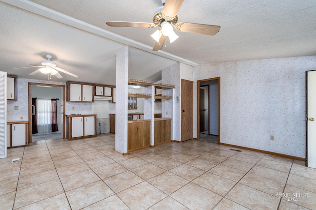 kitchen with ceiling fan, light tile patterned floors, lofted ceiling with beams, and a textured ceiling