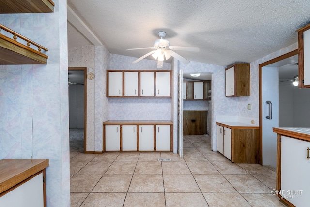 kitchen featuring a textured ceiling, vaulted ceiling, ceiling fan, light tile patterned floors, and white cabinetry