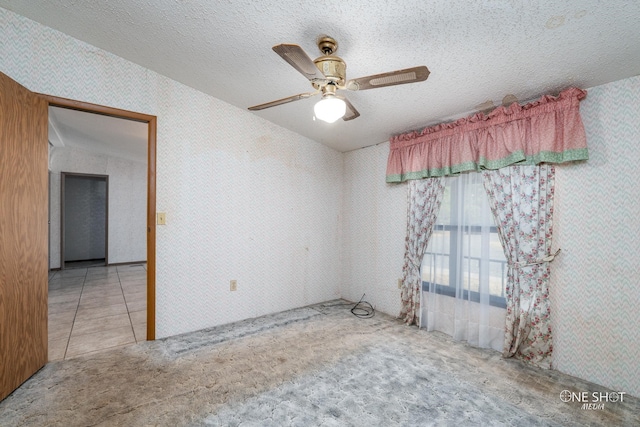 unfurnished room featuring ceiling fan, lofted ceiling, a textured ceiling, and light tile patterned floors