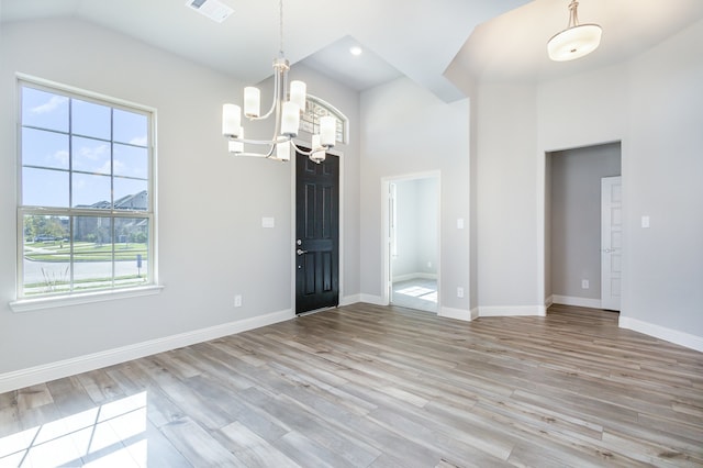 interior space with light hardwood / wood-style flooring, a chandelier, and lofted ceiling