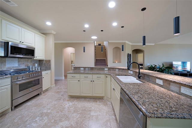 kitchen featuring decorative backsplash, appliances with stainless steel finishes, dark stone counters, sink, and decorative light fixtures