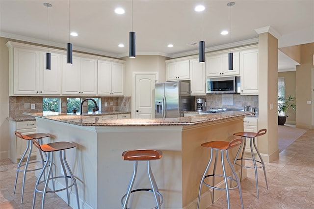 kitchen with light stone counters, a kitchen island with sink, stainless steel appliances, and hanging light fixtures