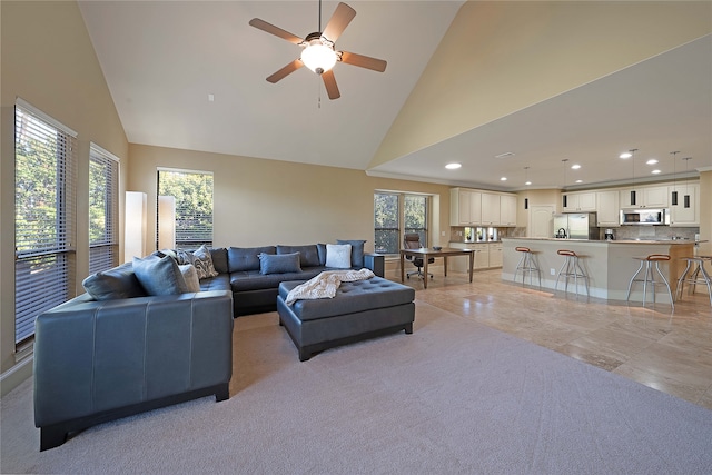 tiled living room with ceiling fan and high vaulted ceiling