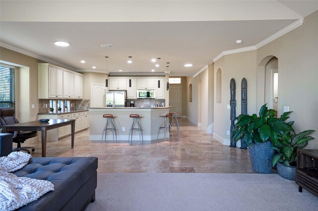 kitchen with tasteful backsplash, stainless steel appliances, hanging light fixtures, and an island with sink