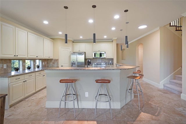 kitchen featuring a center island, light stone counters, hanging light fixtures, and appliances with stainless steel finishes