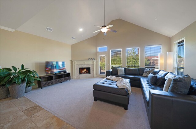 living room with a high end fireplace, high vaulted ceiling, light colored carpet, and ceiling fan