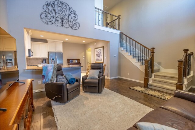 living room featuring a towering ceiling and dark hardwood / wood-style floors